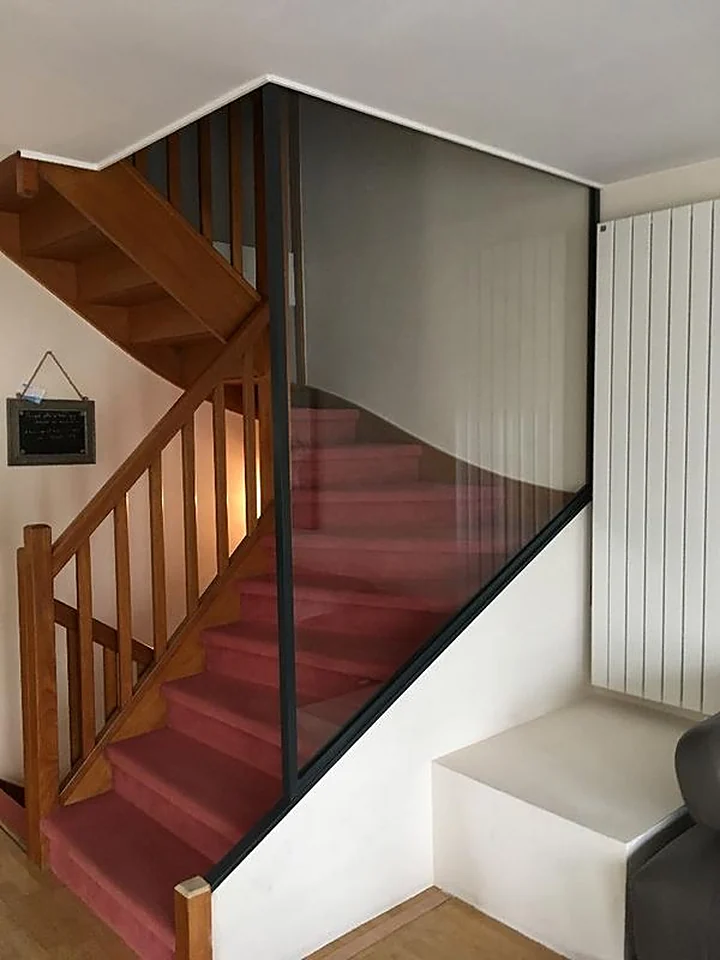 Cloison vitrée à profilé noir séparant un escalier en bois du séjour