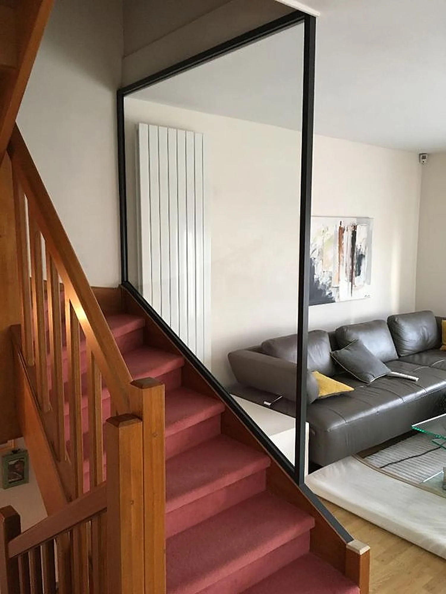 Cloison vitrée à profilé noir le long d'un escalier en bois, côté salon